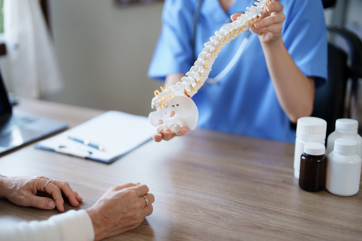 Portrait of a female doctor talking to an elderly patient about herniated disc deterioration from long hours of work